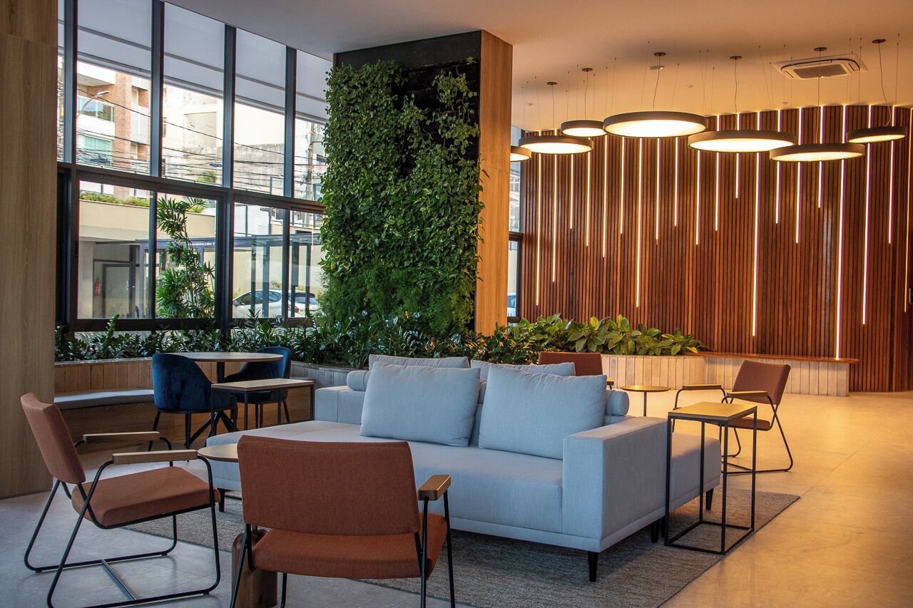 Ein modernes Interieur mit einer Couch, Sesseln, einer vertikalen Begrünung und Pendelleuchten.