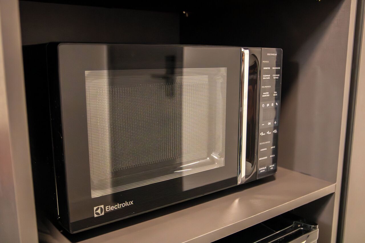 A black Electrolux microwave oven with a digital display and control panel on a shelf.