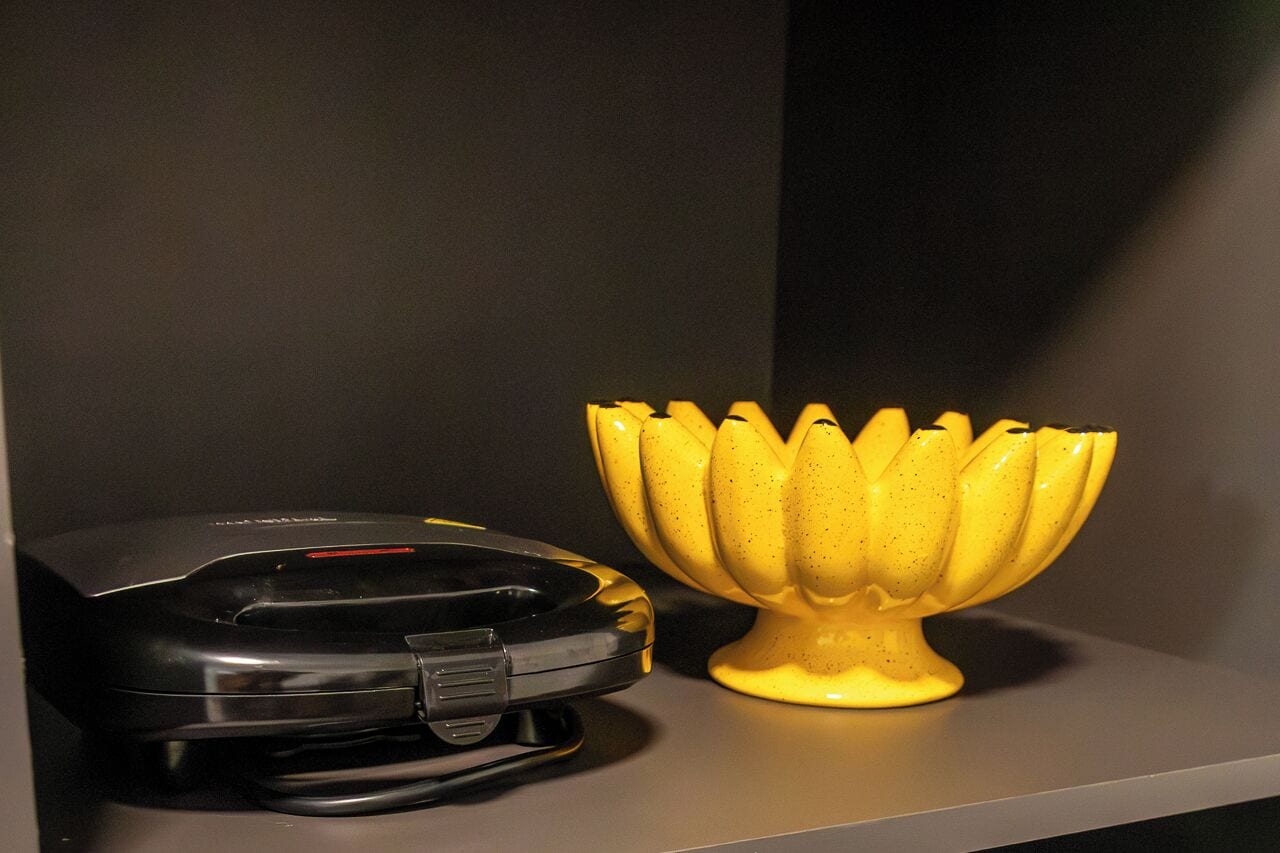 Ein schwarzer Drucker und ein gelbes, lotusblumenförmiges Objekt auf einem Regal.