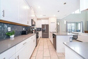 A modern kitchen with white cabinets, a central island, and a built-in oven. - 5 BD/ 5 BA/ Storey Lake (4352 QS) (Kissimmee)
