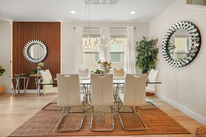 A modern dining area with a round table, white chairs, and a hanging light fixture. - 5 BD/ 5 BA/ Encore Resort at Reunion (280 PC) (Kissimmee)