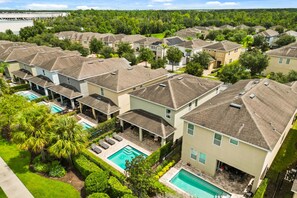 A residential area with multiple houses, a swimming pool, and a large building in the background. - 5 BD/ 5 BA/ Encore Resort at Reunion (280 PC) (Kissimmee)