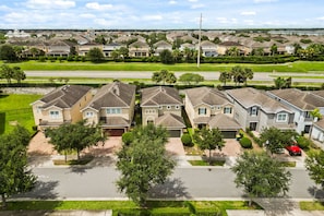 A residential area with houses, a road, and a red car parked in the driveway. - 5 BD/ 5 BA/ Encore Resort at Reunion (280 PC) (Kissimmee)