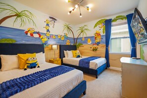 A hotel room with two beds, a desk, and a TV. The room features a beach-themed mural with minions and palm trees. - 5 BD/ 5 BA/ Encore Resort at Reunion (280 PC) (Kissimmee)