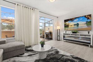 A modern living room with a grey sofa, a marble coffee table, and a large flat-screen TV. - 3 BD/ 2.5 BA/ Fiesta Key (1286 SB) (Kissimmee)