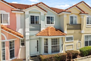 A row of townhouses with a shared courtyard, featuring balconies and a central entrance. - 3 BD/ 2.5 BA/ Fiesta Key (1286 SB) (Kissimmee)