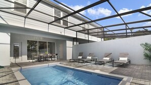 Ein Schwimmbecken mit Liegestühlen und einer Terrassenfläche.