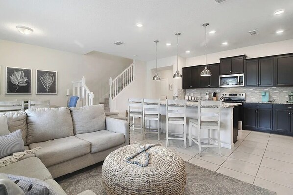 A modern kitchen with dark cabinets, a white island, and a stainless steel microwave. - 5 BD/ 4.5 BA/ Windsor Island (131 JW) (Davenport)
