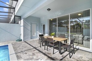 An outdoor patio with a pool, a dining table with chairs, and a sliding glass door leading to a deck. - 5 BD/ 4.5 BA/ Windsor Island (131 JW) (Davenport)