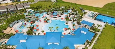 A resort with a central pool, multiple lounge areas, and a large building with a blue roof.