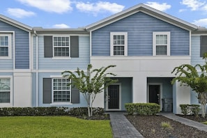 A two-story residential building with a front entrance, a small garden area, and a paved walkway. - 5 BD/ 4.5 BA/ Windsor Island (131 JW) (Davenport)