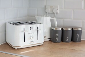 A kitchen with a white toaster, a white kettle, and three dark containers labeled coffee, tea, and sugar. - Spacious 5BR Birmingham Home | Near Edgbaston (Birmingham)