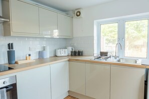Eine moderne Küche mit weißen Schränken, einem eingebauten Backofen, einem Toaster und einem Fenster mit Blick auf Grünflächen.