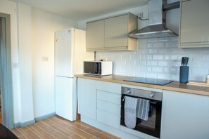 Cozinha moderna com micro-ondas embutido, forno e exaustor de aço inoxidável.