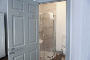 Un baño con ducha envuelta en vidrio, un lavabo blanco y un inodoro.