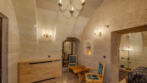 Quarto com teto abobadado, mobiliário de madeira e lustre.