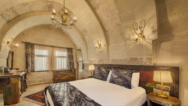 Um quarto espaçoso com uma cama grande, cabeceira de madeira e um candelabro.