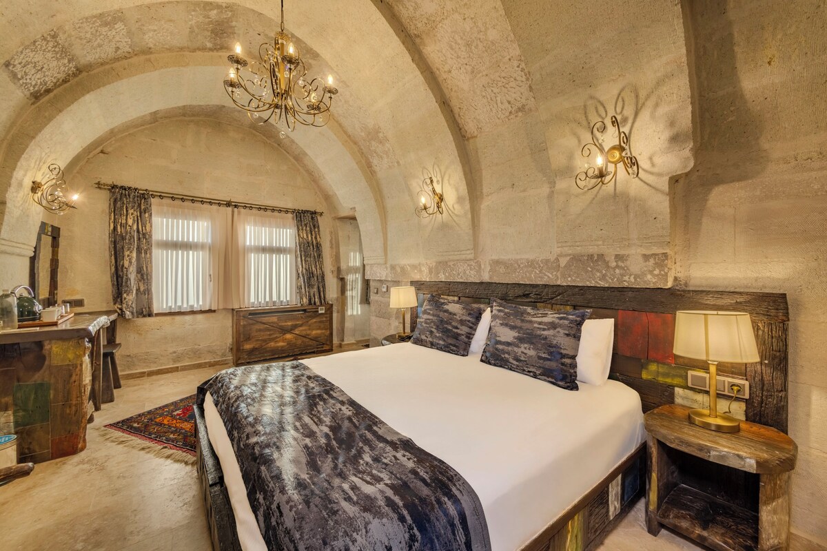 A spacious bedroom with a large bed, a wooden headboard, and a chandelier.