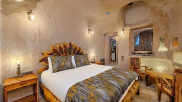 Une chambre rustique avec un grand lit, des meubles en bois et un mur en pierre.