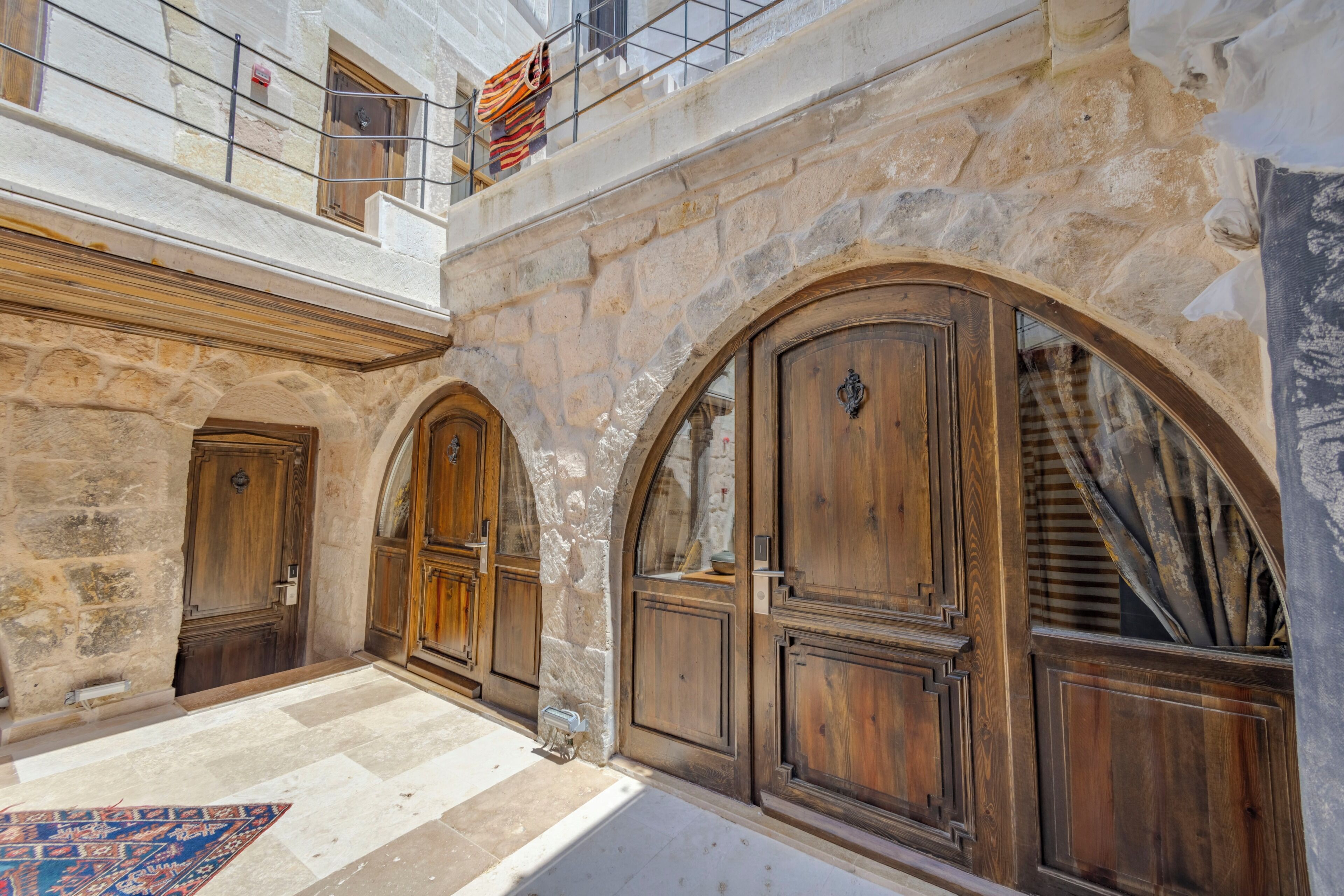 Un patio interior con paredes de piedra, puertas de madera y suelo de baldosas.