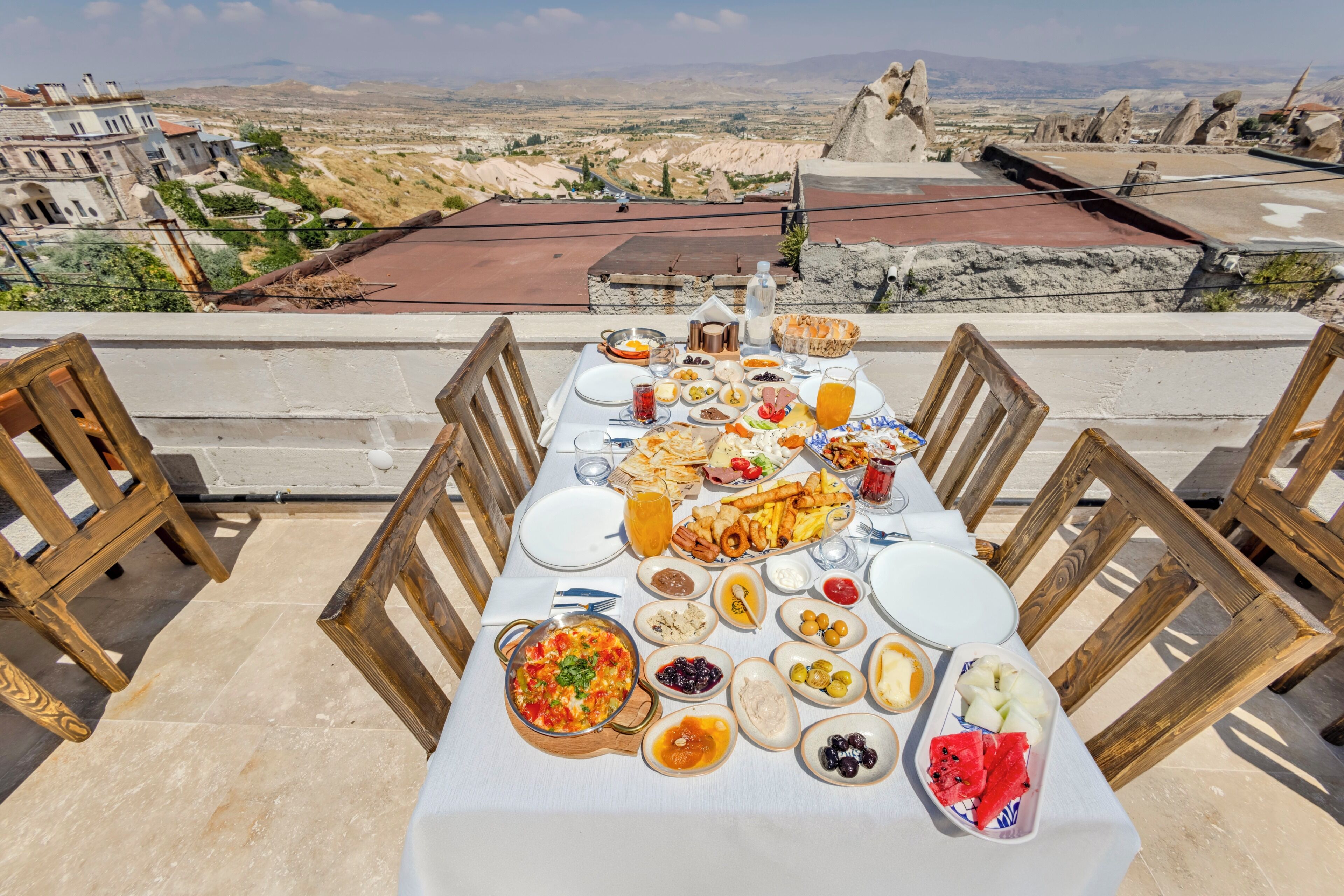 A table set with a variety of dishes and drinks, overlooking a mountainous landscape.