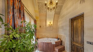 A bathroom with a wooden bathtub, a chandelier, and a large wooden door. - VETUS CAVE CAPPADOCIA (NEVŞEHIR)