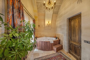 A bathroom with a wooden bathtub, a chandelier, and a large wooden door. - VETUS CAVE CAPPADOCIA (NEVŞEHIR)