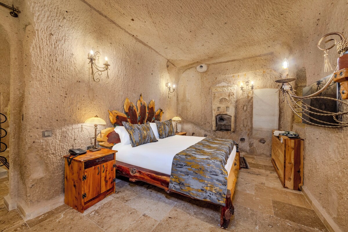 A bedroom with a large bed, wooden furniture, and wall-mounted lighting.