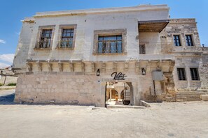 A two-story building with a stone facade, a sign reading 'Vetus Cave Cappadocia,' and a small entrance with steps leading up to it. - VETUS CAVE CAPPADOCIA (NEVŞEHIR)