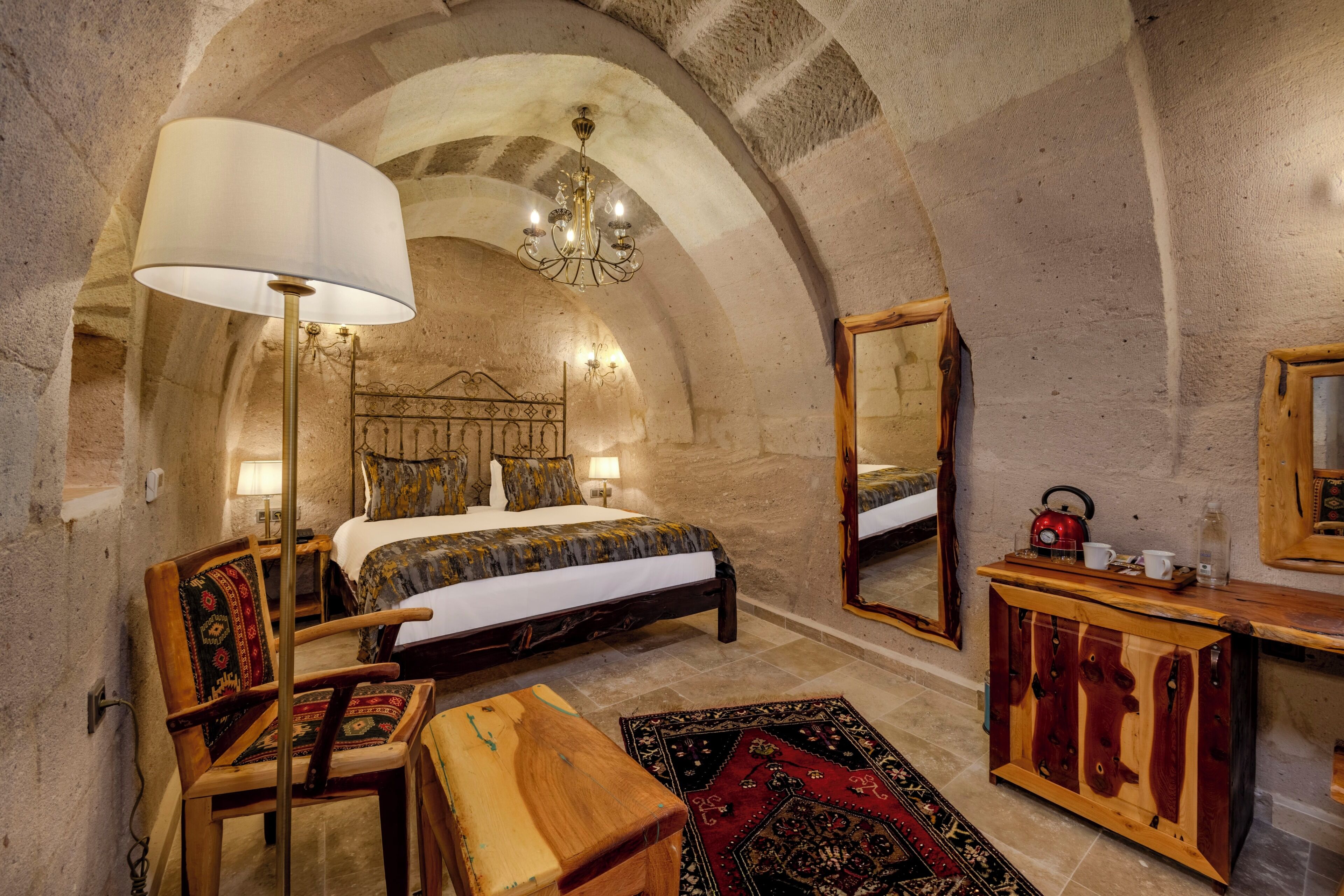 Une chambre à coucher avec un grand lit, une commode en bois, un miroir et un lustre.