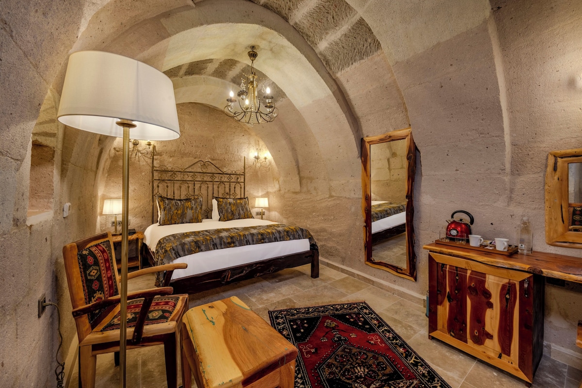 A bedroom with a large bed, a wooden dresser, a mirror, and a chandelier.