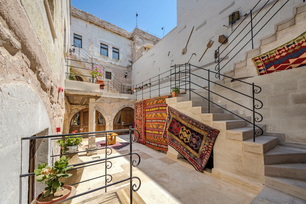 Un callejón estrecho con una escalera que conduce a un nivel superior, paredes de piedra y plantas en macetas.