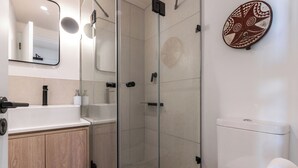 A modern bathroom with a glass shower enclosure, a wooden vanity, and a toilet. - Neo-African studio in Cape Town with spectacular rooftop swimming views (Cape Town)
