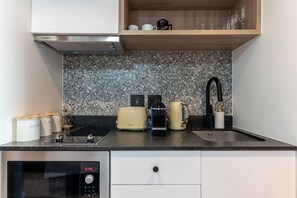 Eine moderne Küche mit Einbauofen, Kaffeemaschine, Toaster und Wasserkocher.