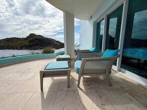 Een balkon met rieten meubilair en uitzicht op zee.