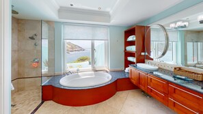 Un baño moderno con una bañera grande, cabina de ducha y tocador con un espejo amplio.