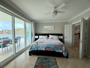 A bedroom with a bed, a ceiling fan, a view of the sea, and a dining area with a table and chairs. - LUXURY WATERFRONT 3 BR 3 BA W/PVT POOL, WRAP-AROUND PATIOS 1st Floor Gated condo (Oyster Bay)