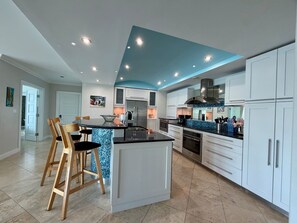 Een moderne keuken met witte kasten, een centraal eiland en een blauwe spatwand.