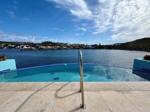 Una piscina con vista despejada al agua y una costa lejana.