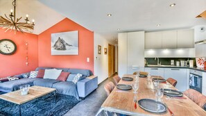 A modern living room with a sofa, dining table set for six, and a kitchen area with cabinets and a sink. - 100m from ski slopes, 2nd floor, terrace, tv, 78m², Les Gets (Les Gets)