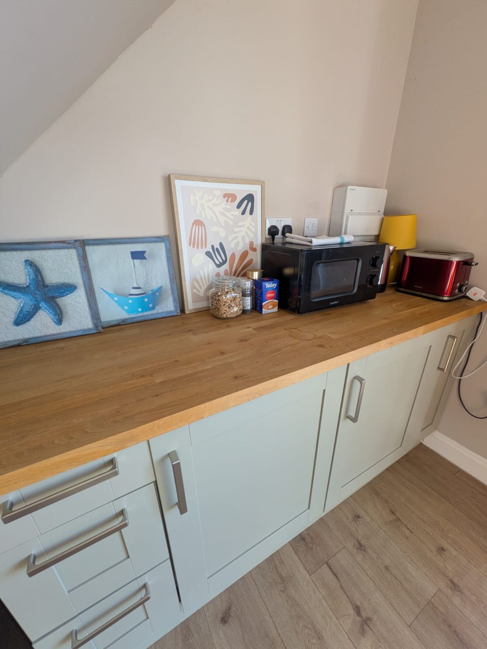 Bright coastal-style kitchenette with microwave, kettle, and toaster