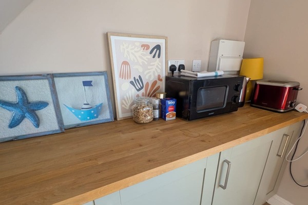 Bright coastal-style kitchenette with microwave, kettle, and toaster