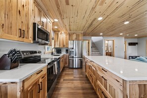 A modern kitchen with wooden cabinets, stainless steel appliances, and a central island. - Yellowstone Retreat w/AC & wrap-around porch. Fly fish, trail riding, snowmobile (Island Park)