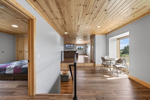 A spacious room with a wooden ceiling, a bed, a desk, and a view of the outdoors. - Yellowstone Retreat w/AC & wrap-around porch. Fly fish, trail riding, snowmobile (Island Park)