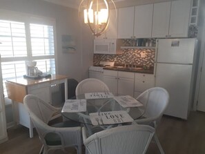 A kitchen with white cabinets, a microwave, a refrigerator, and a dining table with chairs. - Luxury at its best at Turtle Crawl Resort (Longboat Key)