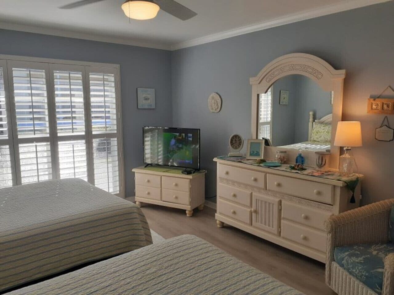 A bedroom with a bed, dresser, television, and a chair.