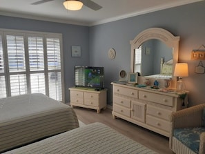 A bedroom with a bed, dresser, television, and a chair. - Luxury at its best at Turtle Crawl Resort (Longboat Key)