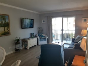 Un saló amb un sofà, una butaca i una televisió penjada a la paret.