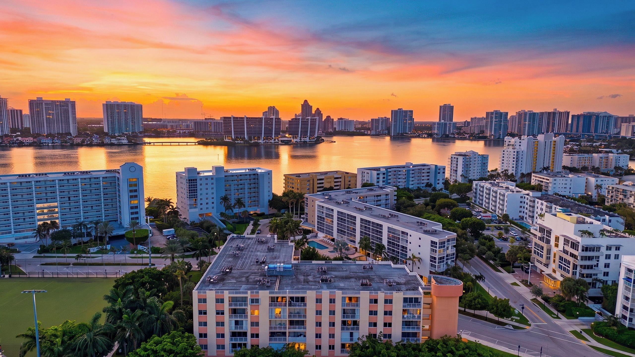 A high-rise hotel with multiple floors, a rooftop pool, and a view of the city skyline at sunset.