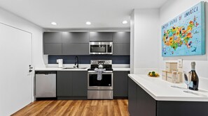 Eine moderne Küche mit grauen Schränken, Edelstahlgeräten, Holzboden und einer Karte der Vereinigten Staaten an der Wand.